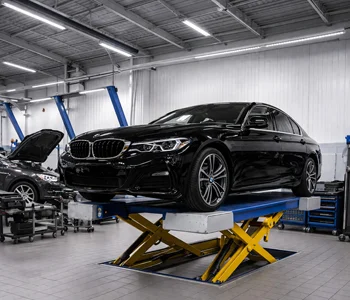 Black BMW 5 Series undergoing professional service and repair on a lift at Azimov Collision