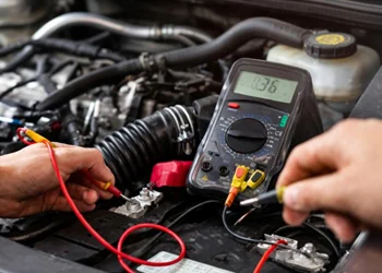 Electrical diagnostics with multimeter in car engine bay at Azimov Collision in California