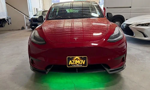 Red Tesla undergoing professional service and diagnostics in the workshop at Azimov Collision